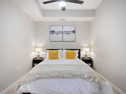 Cozy bedroom with a king-size bed, soft lighting, modern decor, and ceiling fan.