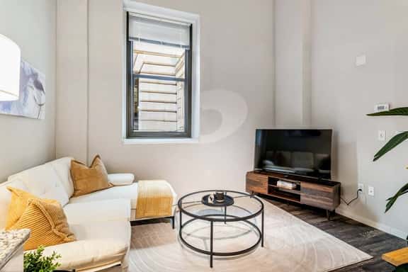 Bright living space with cozy seating, smart TV, and a sleek, modern design.