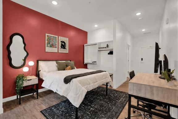 Modern bedroom with bold accent wall, workspace, and cozy designer touches
