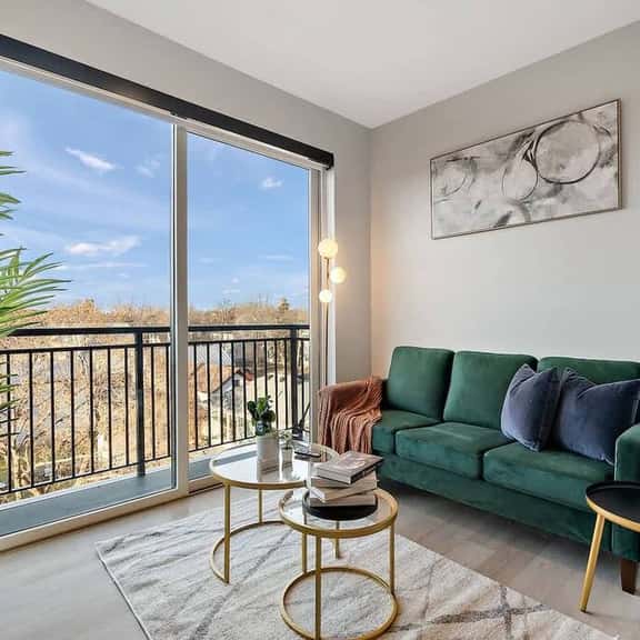 right, stylish living space with lush green sofa, modern art, and balcony views.