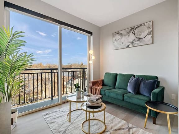 right, stylish living space with lush green sofa, modern art, and balcony views.