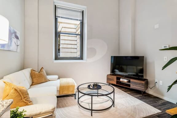 Bright living space with cozy seating, smart TV, and a sleek, modern design.