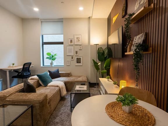Cozy modern lounge with workspace, dining nook, and stylish TV wall