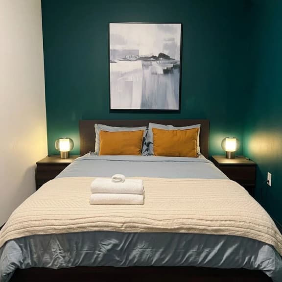Cozy modern bedroom with teal accent wall and warm bedside lighting